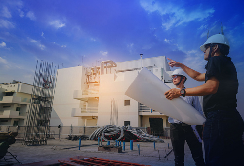 A man holding construction materials in front of a building.