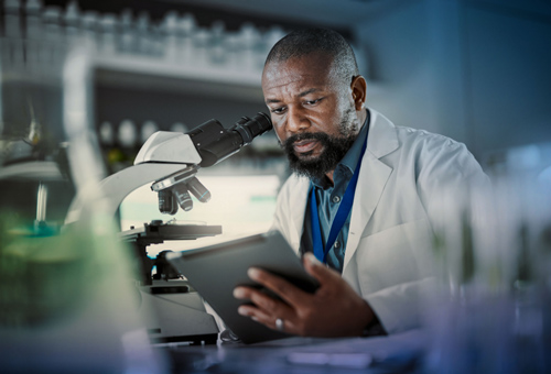 A man in lab coat looking at an ipad.