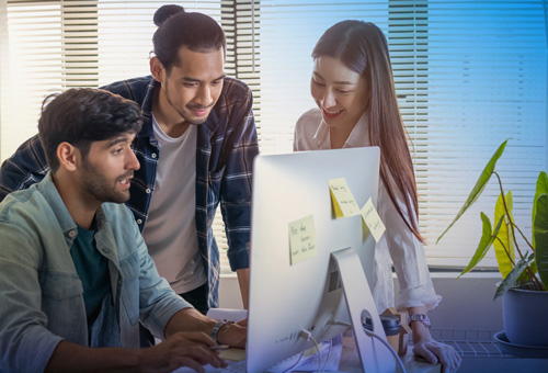 Three people are looking at a computer screen.