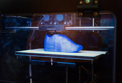 A 3 d printer is shown with a blue shoe.