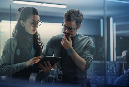 Two people looking at a tablet in the dark.