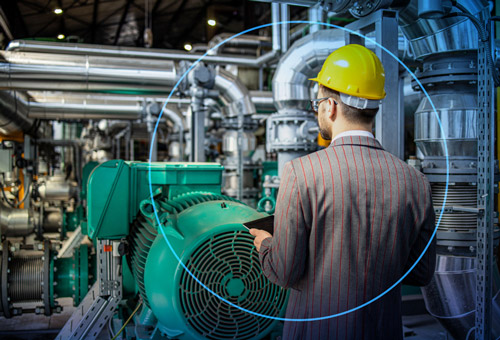 A man in a suit and hard hat standing next to an industrial machine.