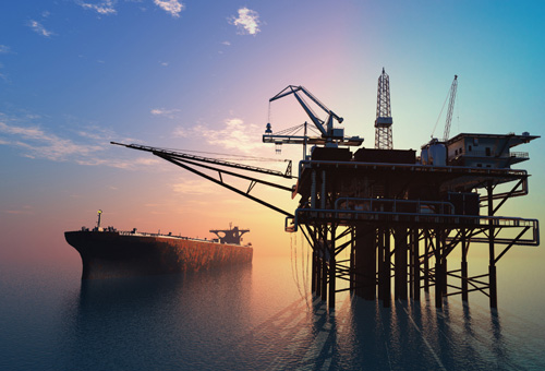 A large rig in the ocean with cranes on it.