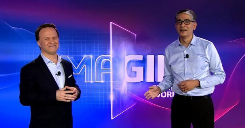 Two men standing in front of a purple background.